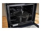 A black cast iron pot with a lid inside an open oven on a rack.