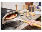 Pizza being removed from outdoor oven with peel.