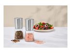 Two spice grinders with peppercorns and pink salt, next to a fresh salad.