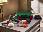 Cordless polisher with accessories and a storage case on a metal workbench.
