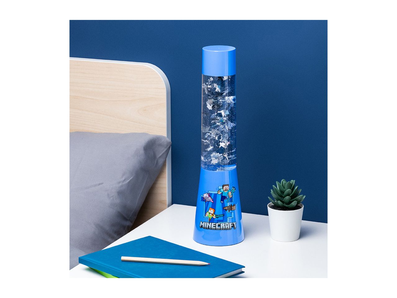 Minecraft lava lamp on a bedside table with a notebook and a small plant.