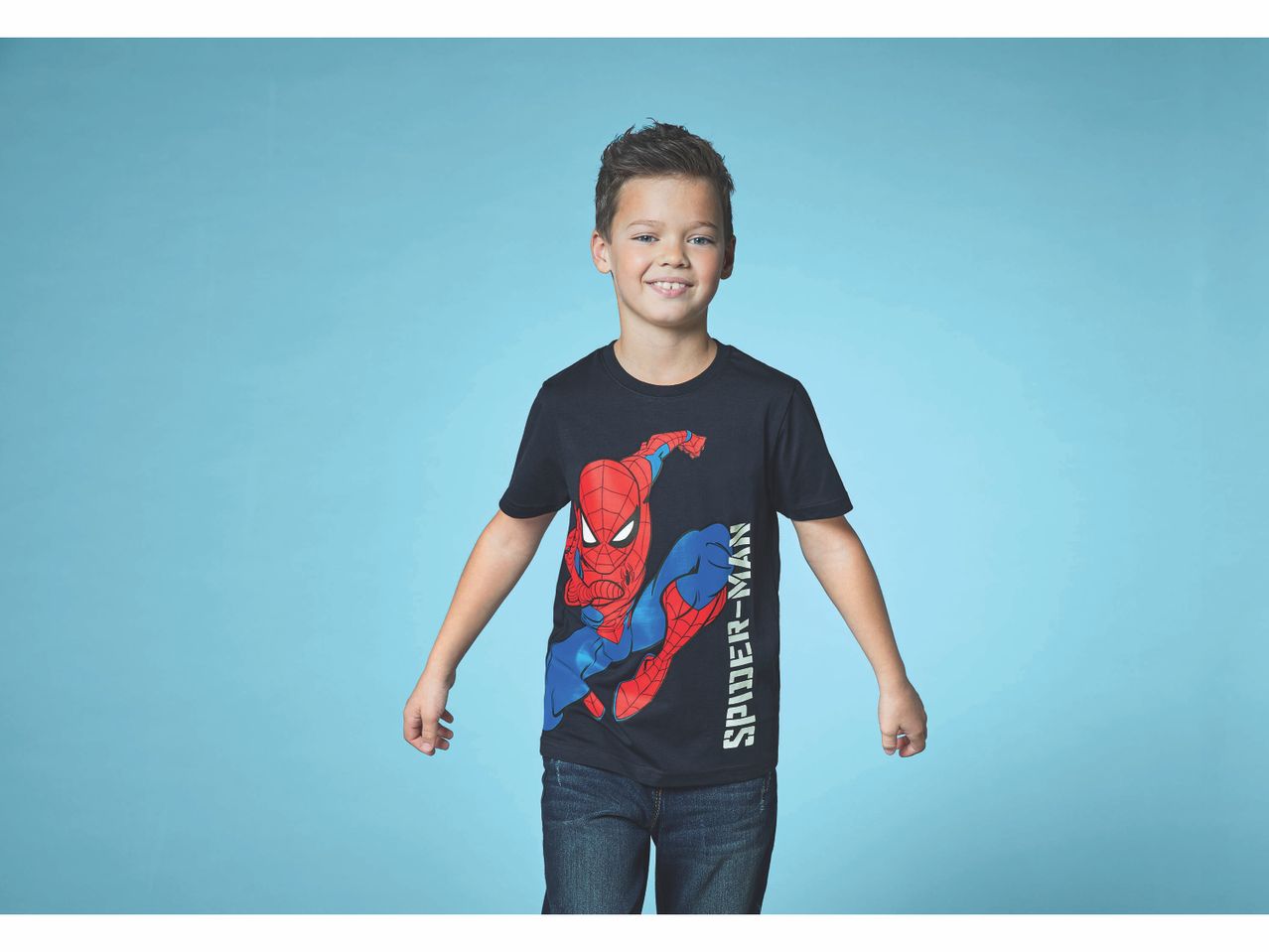 Un ragazzo sorridente indossa una maglietta nera di Spider-Man e jeans.