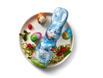 Blue foil-wrapped chocolate bunny with three foil-wrapped chocolate eggs on a plate.