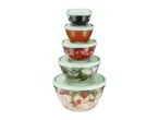 A stack of five nesting glass mixing bowls with lids, featuring fruit and vegetable designs.