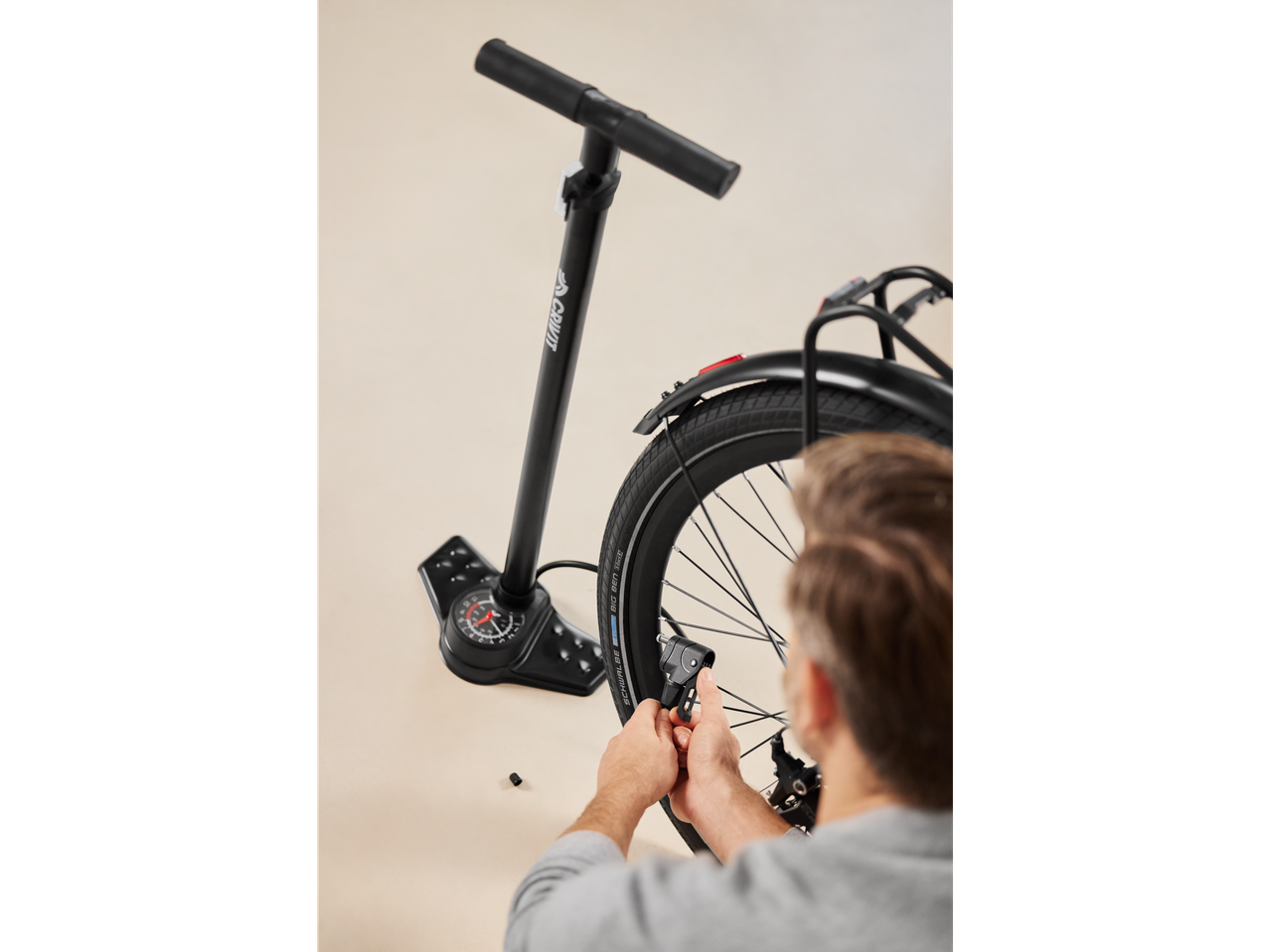 Man inflating a bicycle tire with a Crivit pump.