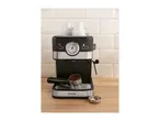 Black and silver espresso machine with two white cups on top, portafilter with coffee grounds.