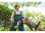 A man uses a Parkside cordless chainsaw to cut a log outdoors.
