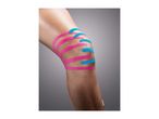 Close-up of a knee with pink and blue kinesiology tape applied