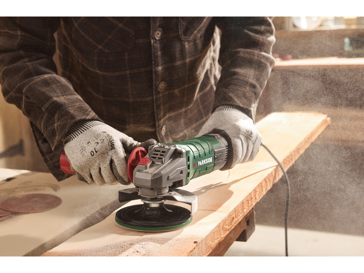 Man sanding a wooden board with a Parkside Performance® PWS 125 angle grinder.