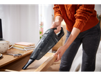 A woman cleans a wooden drawer using a Silvercrest handheld vacuum.