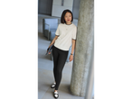 Woman in a white short-sleeved top, black leggings, and black and white loafers.