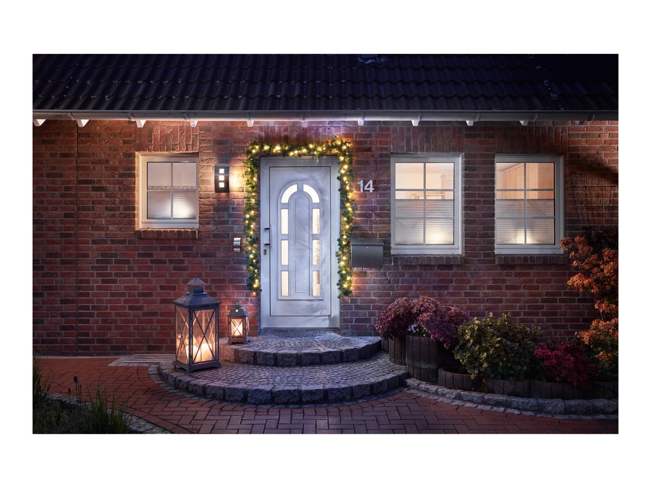 House entrance with festive lighting, lanterns, and decorative plants.