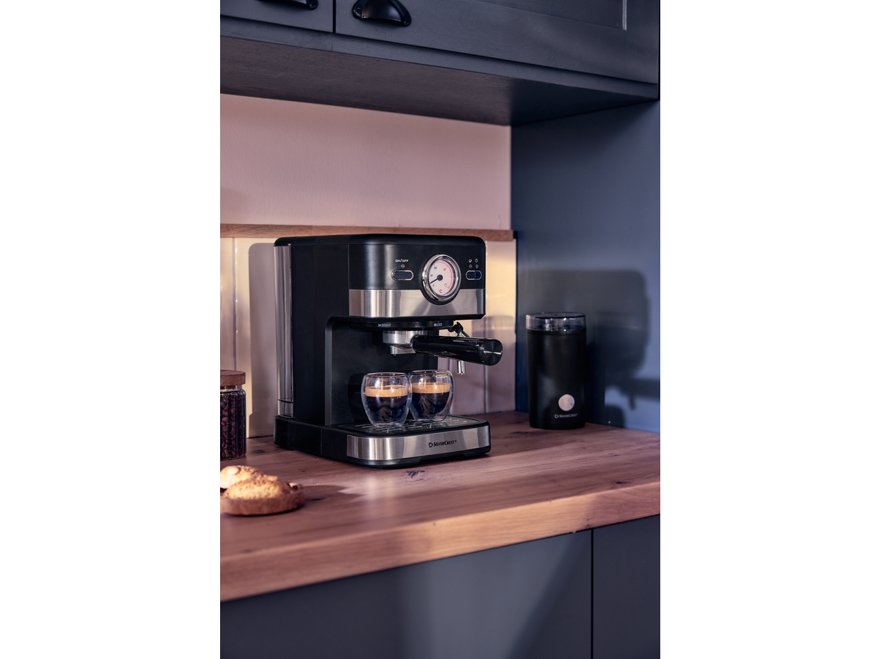 Două pahare cu perete dublu cu espresso pe un aparat de cafea într-o bucătărie modernă.
