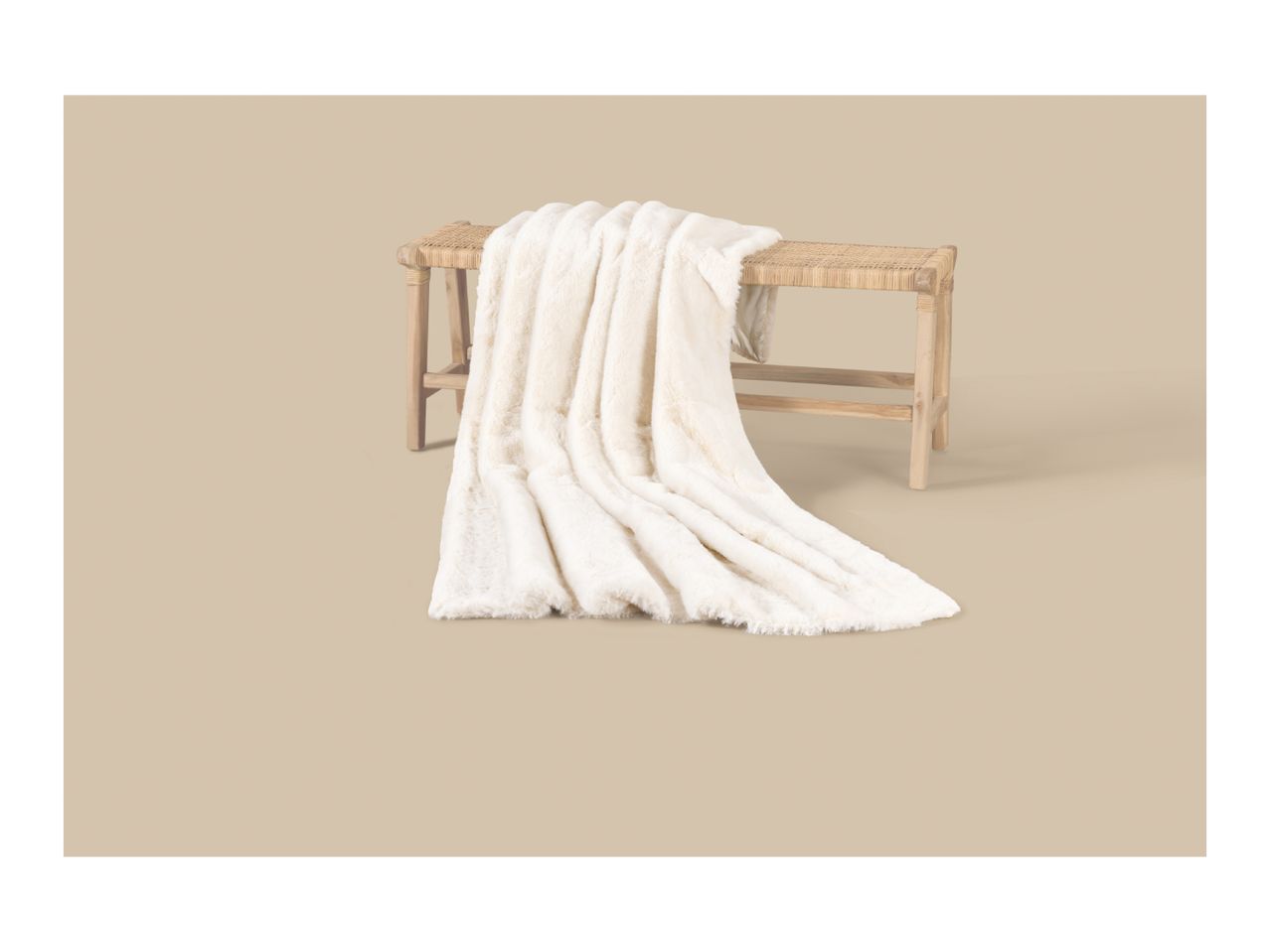 A soft, cream-colored faux fur blanket draped over a rustic wooden bench.