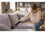 Woman using a SILVERCREST® Mini Cordless Handheld Vacuum Cleaner to clean a sofa.