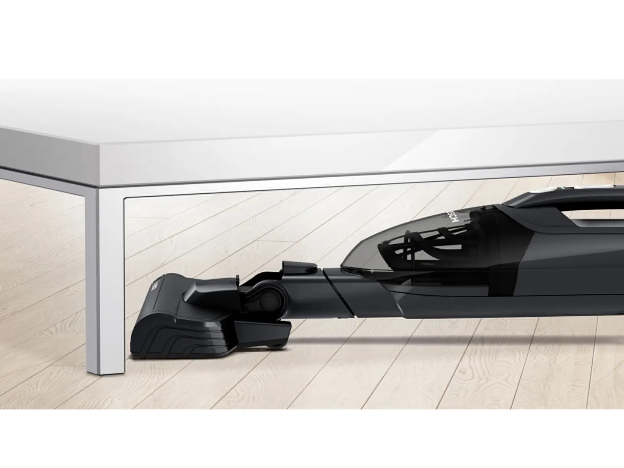 Aspirator vertical 2 în 1 sub o masă albă pe o podea din lemn.