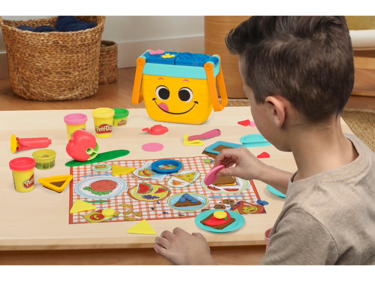 Bērns spēlējas ar Play-Doh plastilīnu, gatavojot ēdienu uz piknika galda.