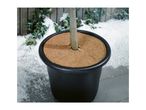 A round coconut fiber mulch mat placed around a potted plant trunk in winter.