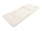 Cream-colored quilted weighted blanket folded on a white background