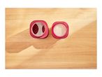 Two red containers on a wooden surface, one with red beans, the other with white beads.