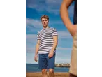 Man in Esmara striped t-shirt and blue shorts on a beach.