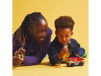 Mother and son playing with a toy fire truck and figures on a yellow background.