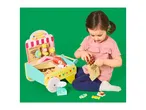 A child playing with a wooden toy candy shop, putting a chocolate bar into a paper bag.