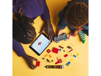 Two people building with construction bricks, using instructions on a tablet.