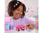 A girl playing with a Barbie dollhouse, camper van, and miniature doll.