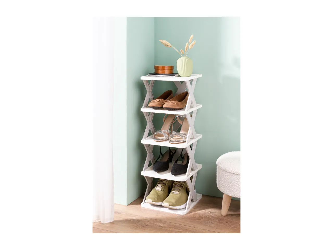 A white shoe rack with various shoes, a vase, and a decorative box.