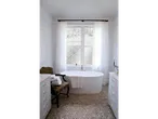 Banheiro elegante com banheira independente, piso de seixos e móveis brancos.