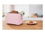 Pink toaster with two slices of bread, next to a plate with a tomato and cream cheese toast.