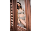 O femeie în lenjerie intimă bej Simone Perele stă lângă o fereastră.