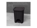 Dark grey rattan-style pedal bin with a textured lid on a tiled floor.