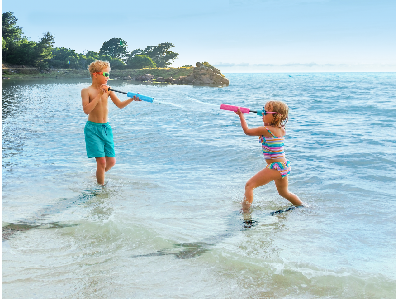 Zwei Kinder spielen mit HAPPY PEOPLE Wasserpistolen im Meer.