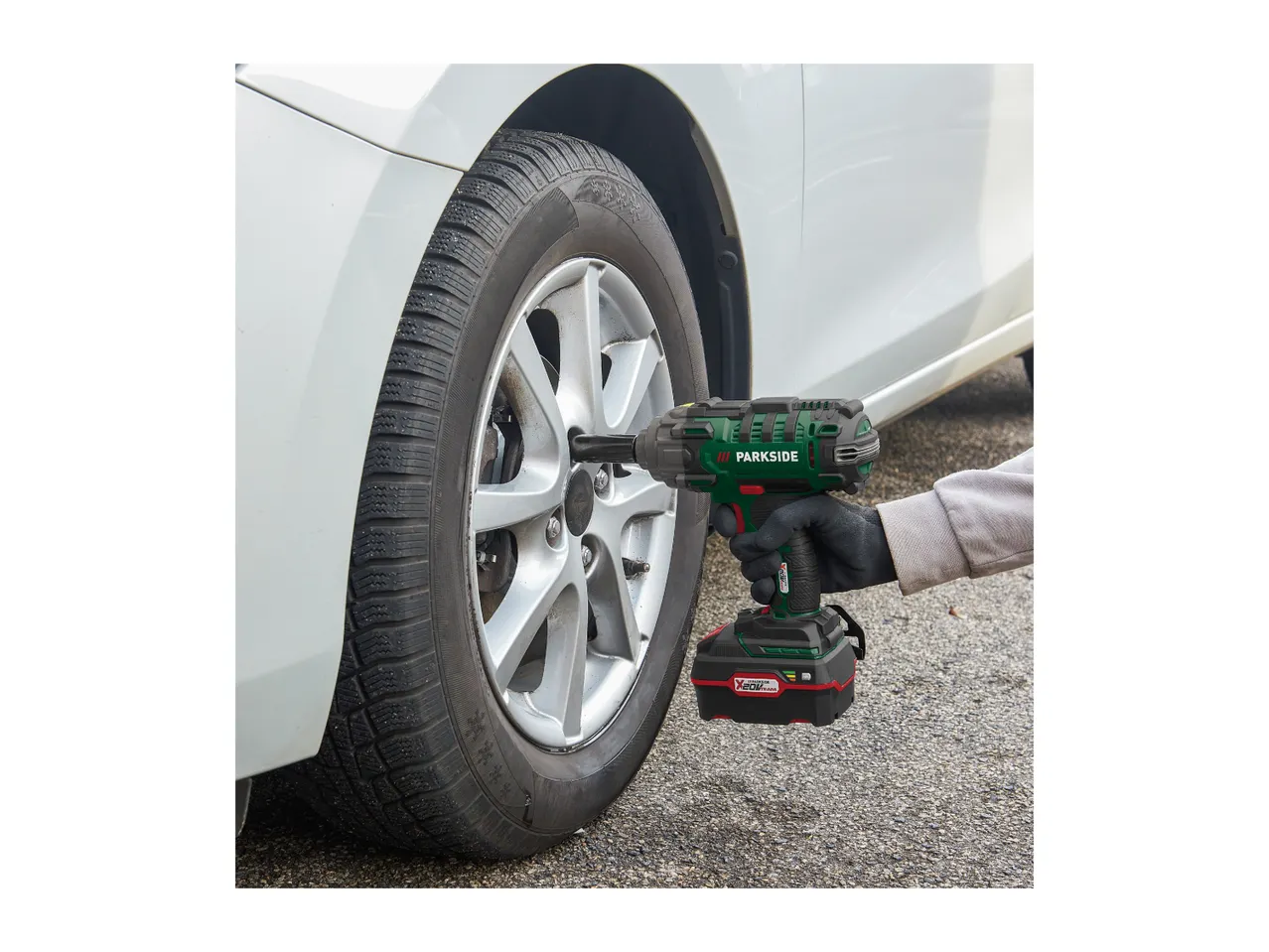 Person using a Parkside impact wrench to change a car tire.