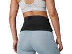 A woman from behind wearing a black waist trimmer, light blue leggings, and a grey sports bra.