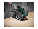 Person in gloves using a mini circular saw with a dust extraction hose on a wooden board.