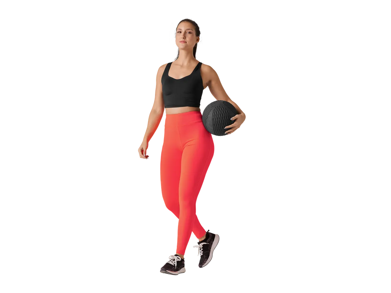 O femeie în ținută sportivă ține o minge medicinală.