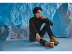 Man wearing black turtleneck, dark jeans, and esmara® Men's Premium Boots, sitting on a blue floor.