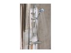 Chrome shower with running water, a sponge, and a wooden brush hanging on the rail.