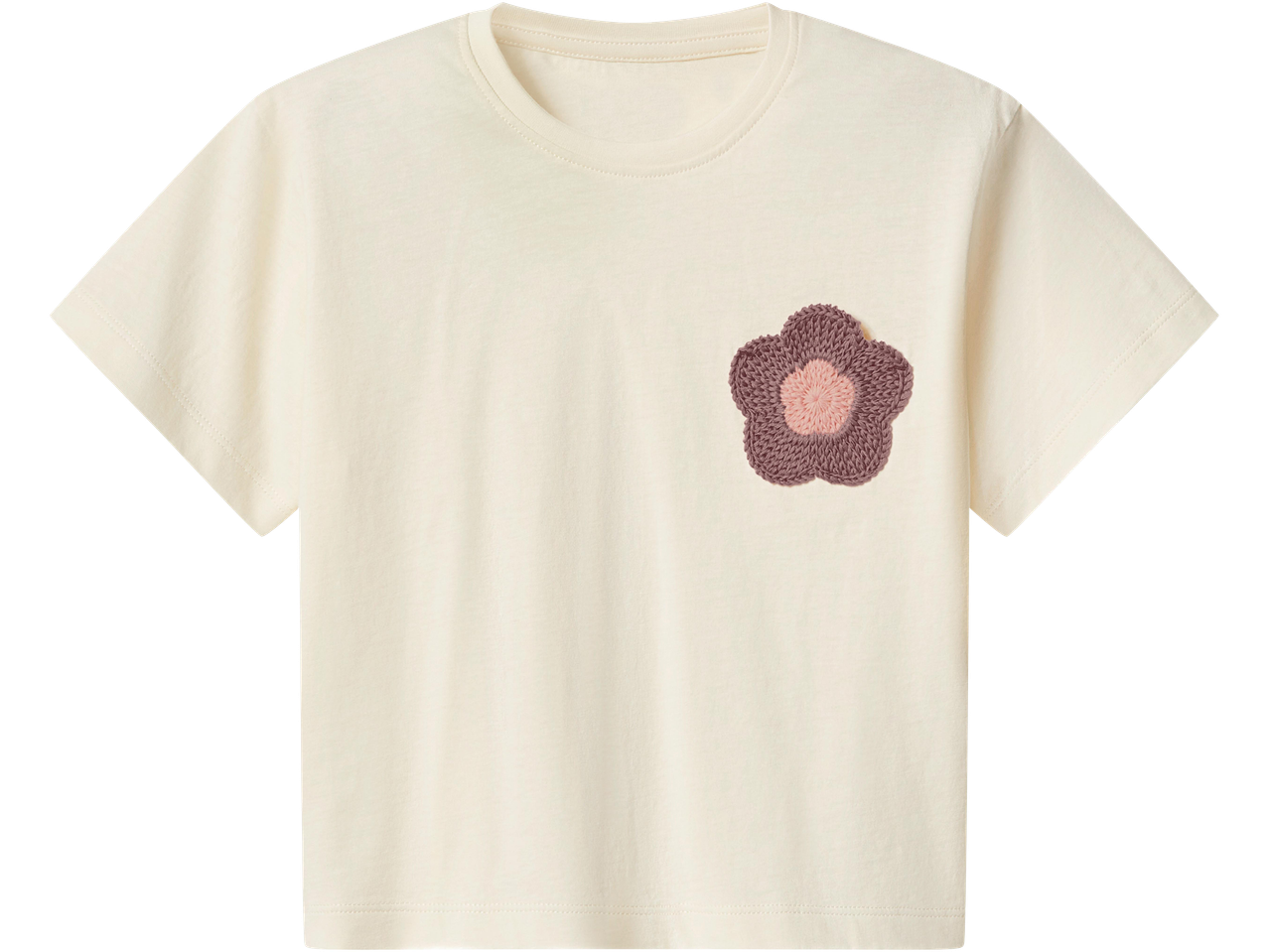 Krémfehér póló horgolt virágmintával a mellkason.