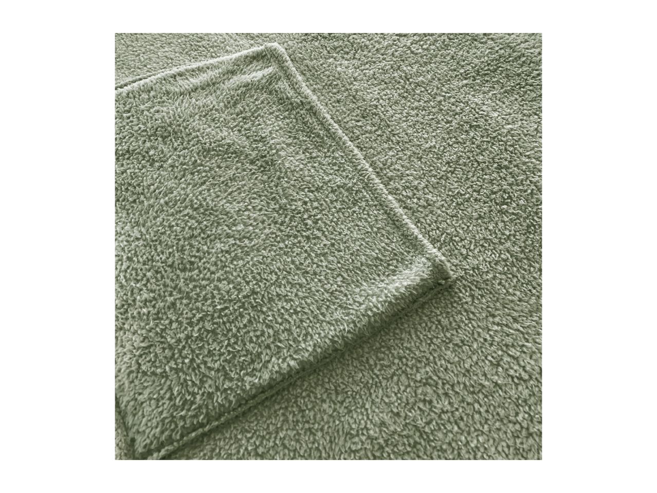 Close-up of a soft, sage green fleece blanket with a visible seam.