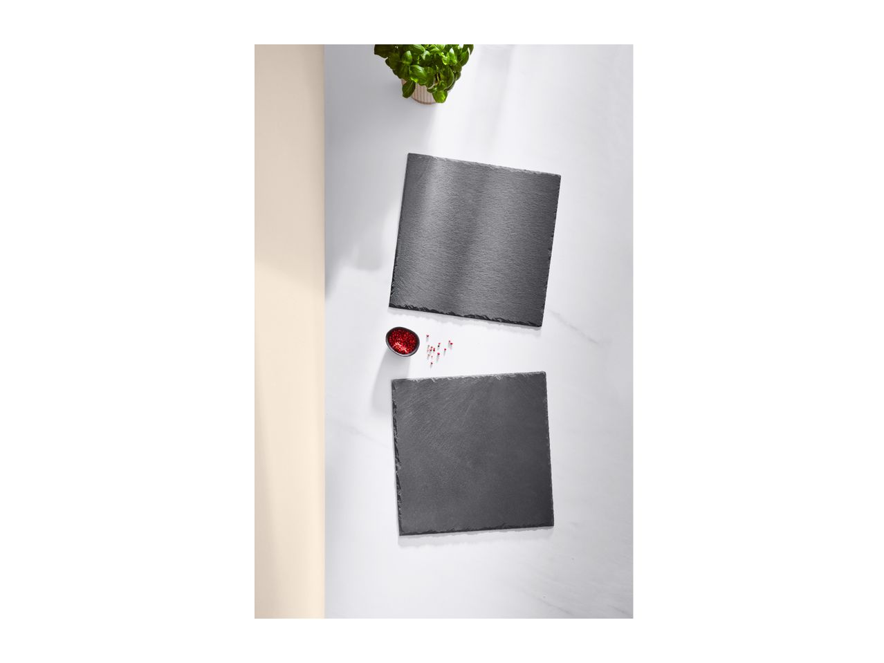 Two rectangular slate serving boards with a small bowl of red peppercorns and a potted plant.