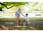 Mother and child in a park; child on a balance bike.