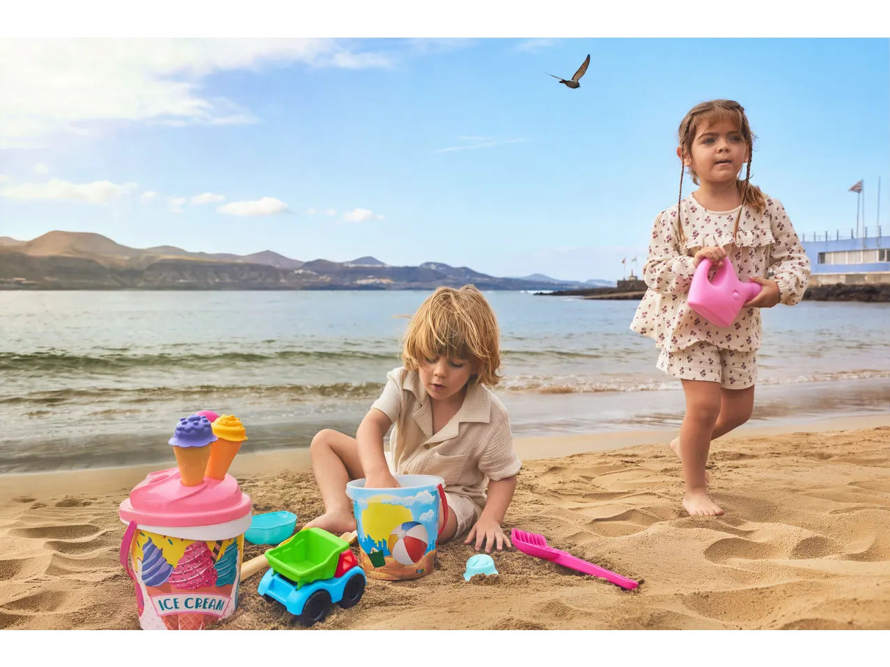 Lupilu Sand Toys: two children playing with buckets, ice cream cones, and a truck on the beach.