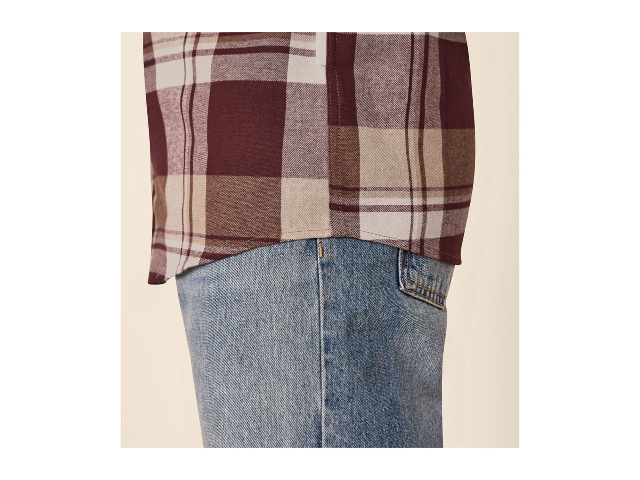 Close-up of a person wearing a plaid shirt and blue jeans.
