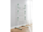 A freestanding, multi-tiered laundry drying rack with light green accents stands on a light wood floor.