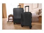 Two black suitcases, one large and one small, in a bedroom setting.
