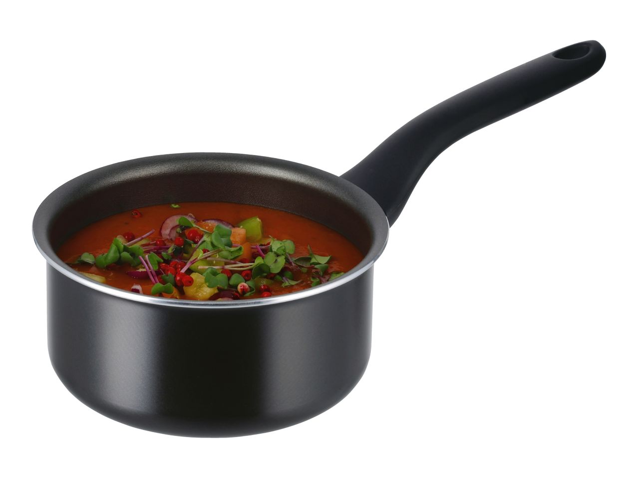 Black saucepan filled with red soup, garnished with fresh herbs and vegetables.